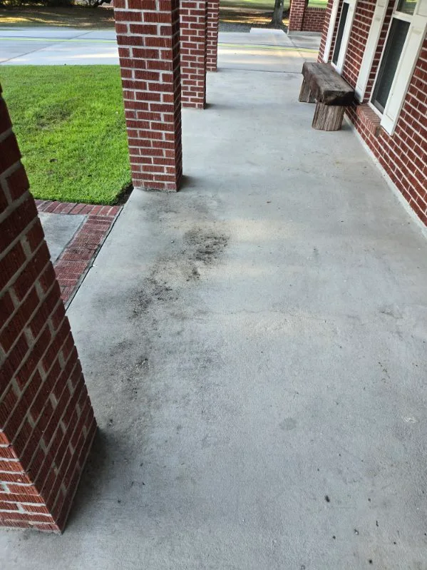 Dark buildup on a covered brick porch before washing